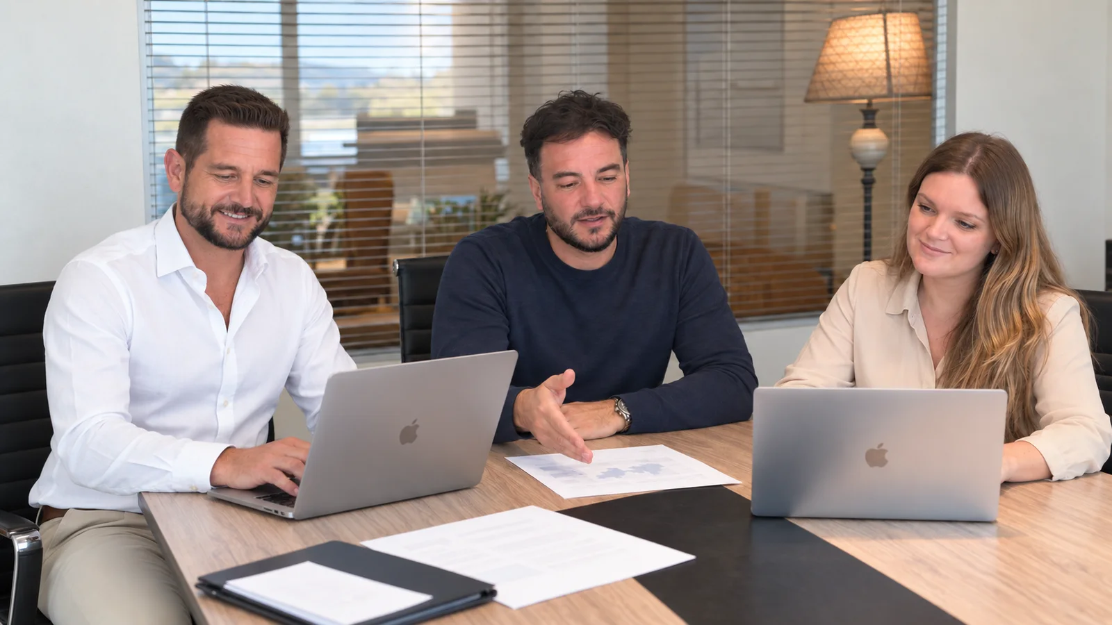 Achia Group team gathered around a table with commercial documents and laptops.